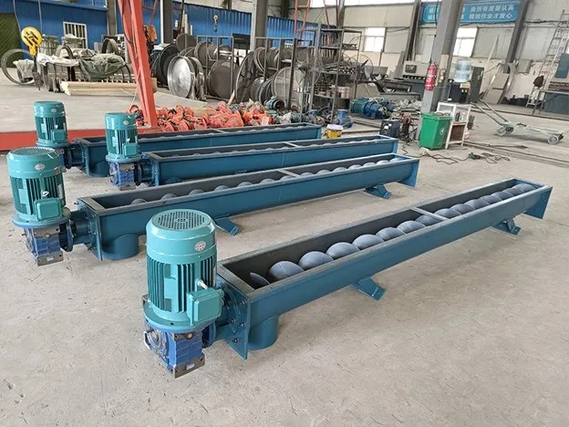 Industrial screw conveyors with electric motors in manufacturing workshop